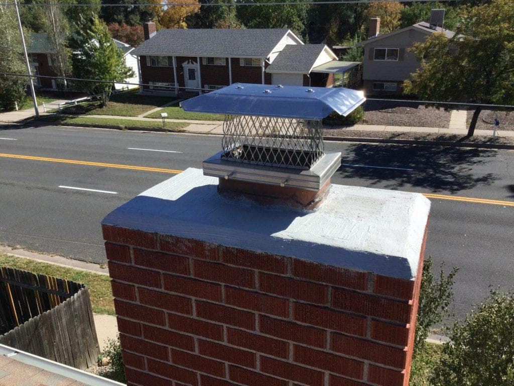 Red brick chimney with a new galvanised chase cap and repaired crown, photographed from the roof of a Kansas City home