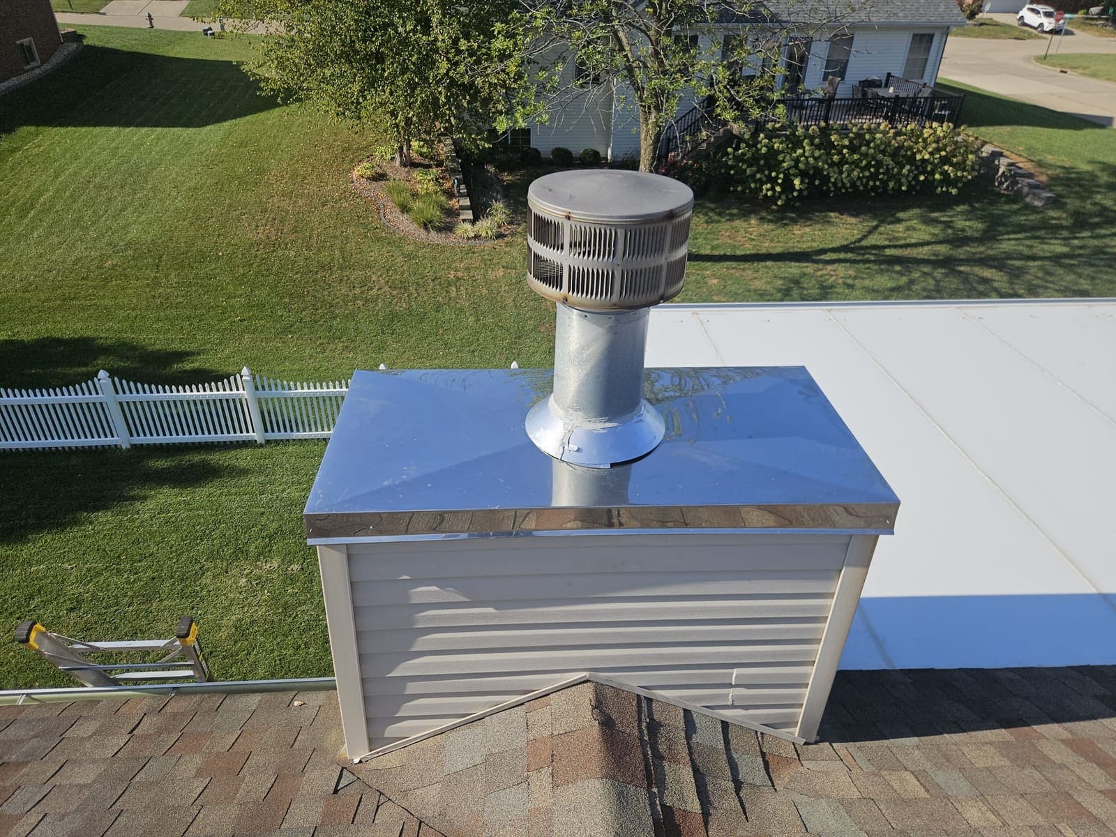 The same chimney chase fitted with a new stainless steel chase cover with a sloped top, sealed around the flue pipe