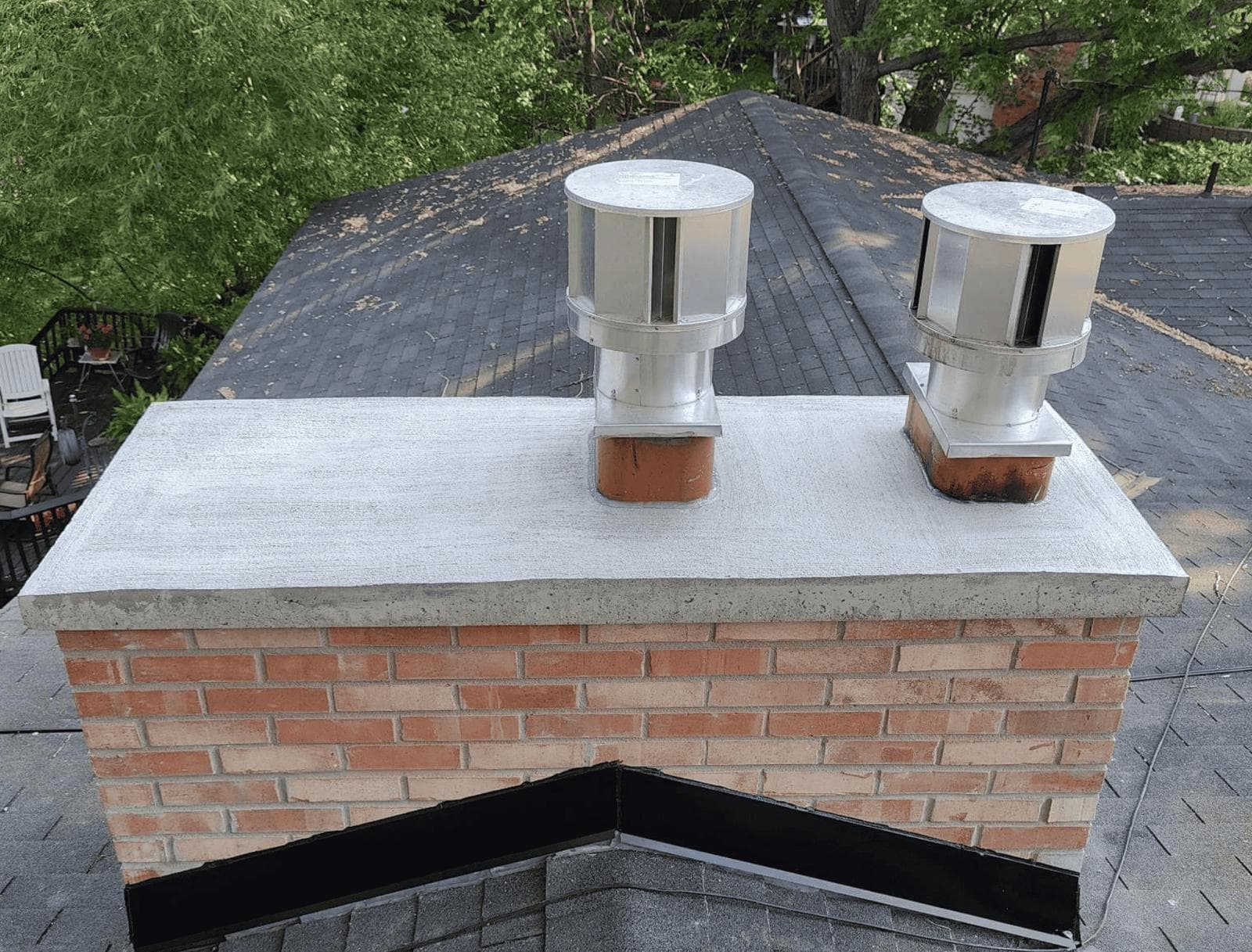The same Kansas City chimney after repointing, with a newly poured concrete crown and two stainless steel caps installed